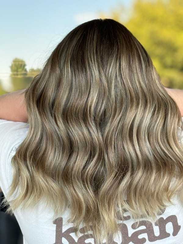 Wavy, shoulder-length hair with blonde and light brown highlights, displayed from the back.